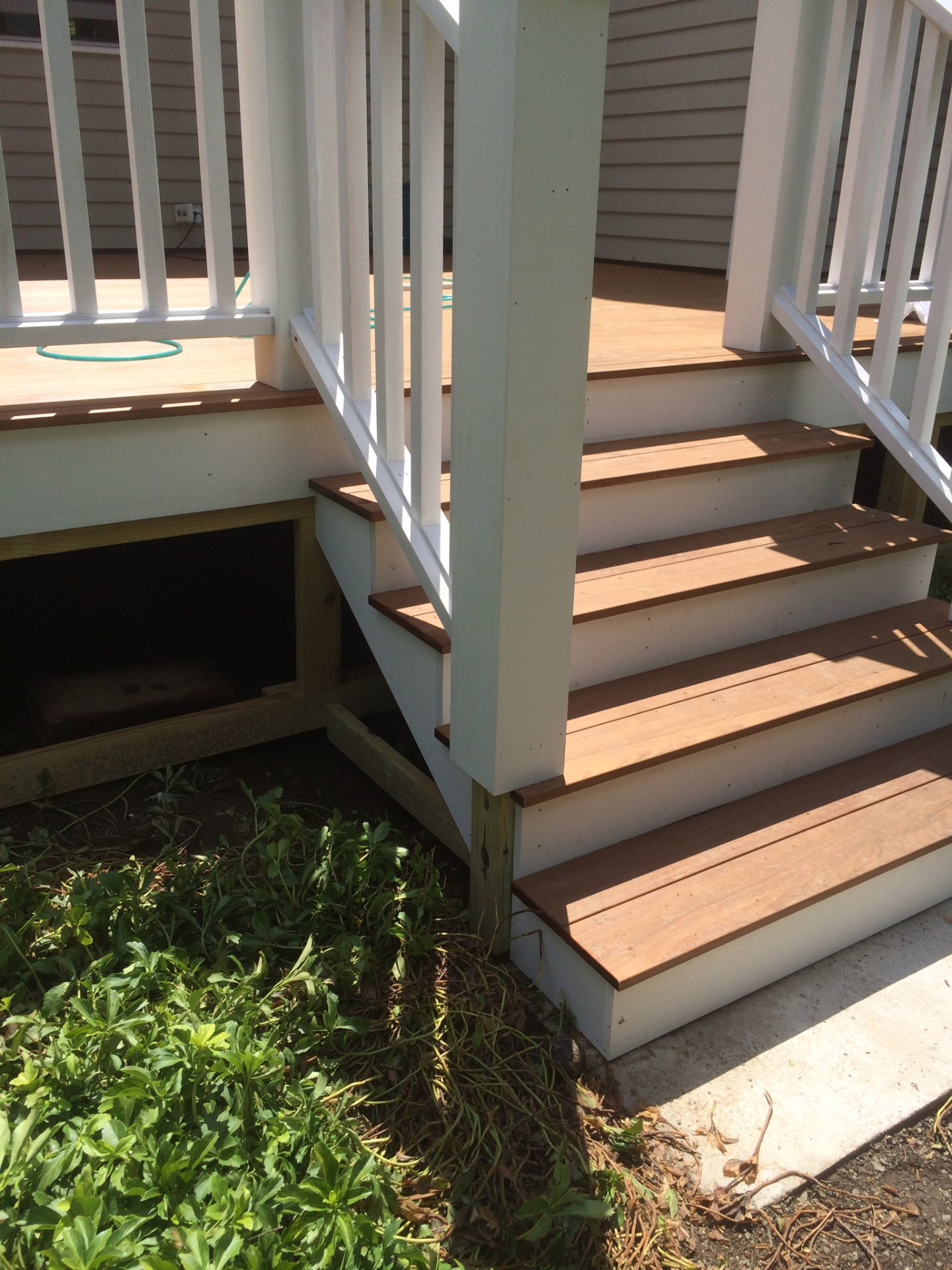 Close-up of a white deck post and rail meeting stair stringers with clean joinery