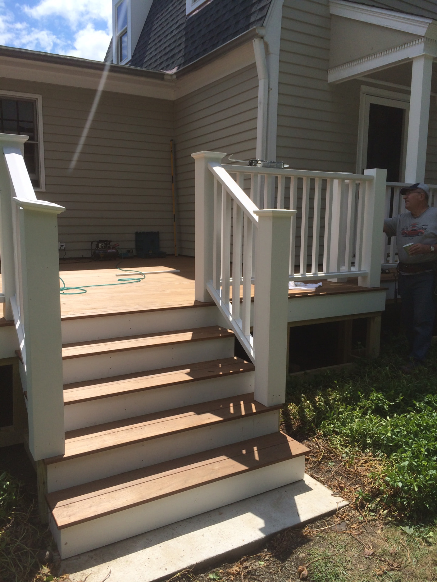 Detail of wide deck stairs with white risers and warm-toned treads leading to a landing