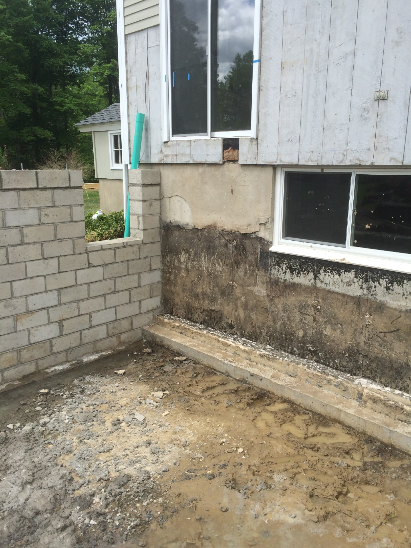 New concrete block wall and waterproofed foundation footing prepared for backfill