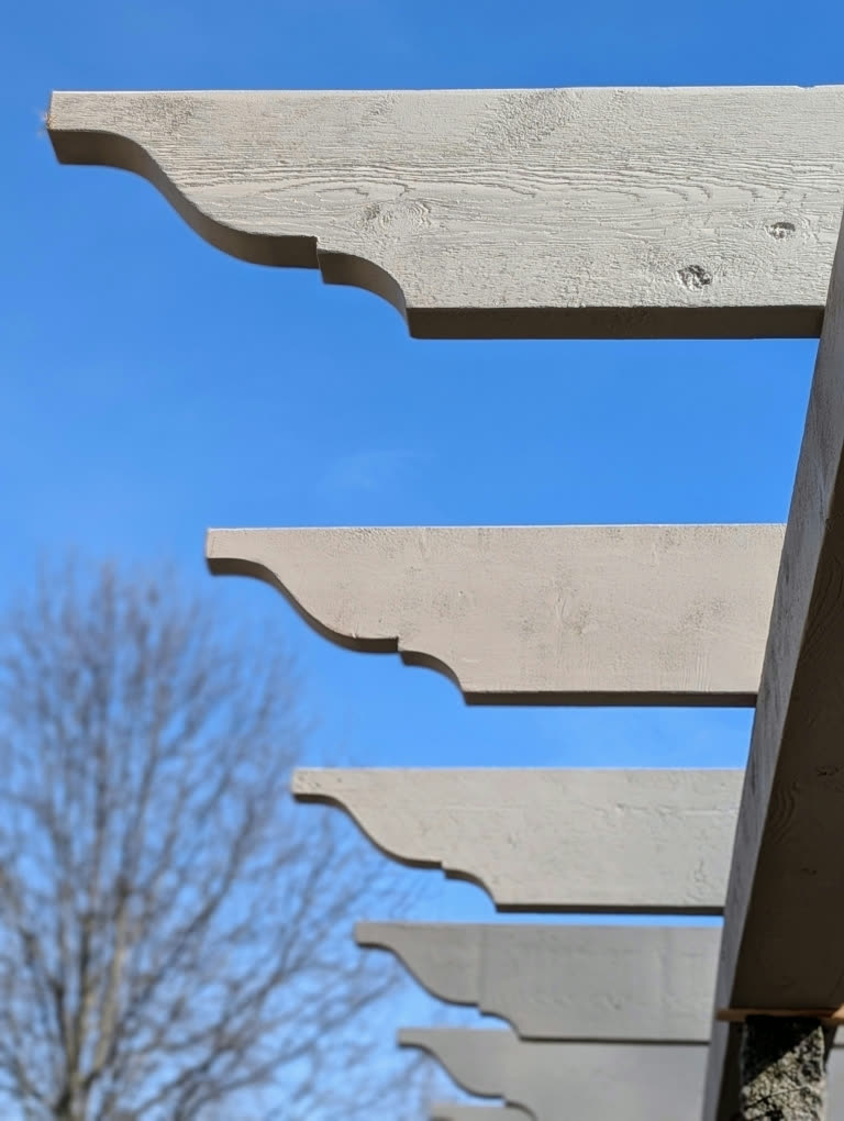 Hand-cut cedar rafter tails silhouetted against a clear blue sky